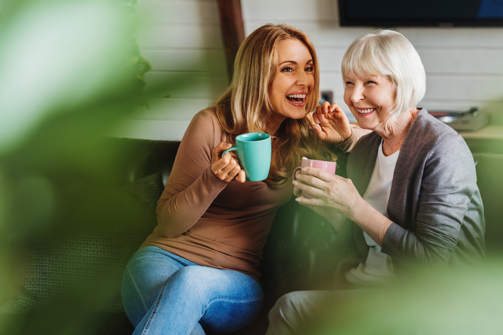 Mom and daughter laughing enjoying a hot beverage
