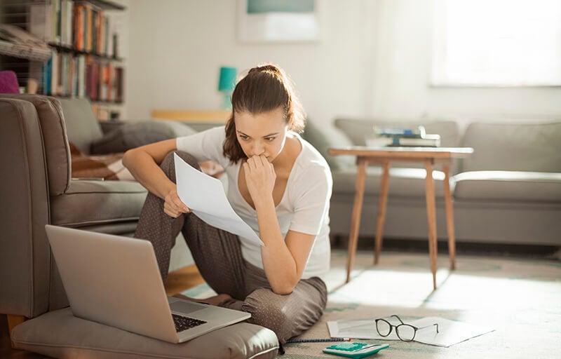 A woman studying her laptop on the floor