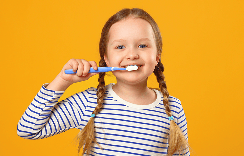 A girl with pigtails pretending to brush her teeth