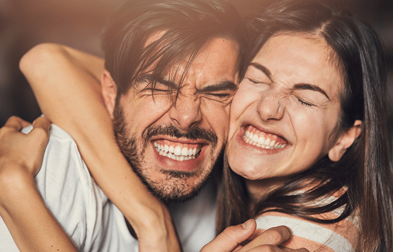 A couple hugging and grinning playfully