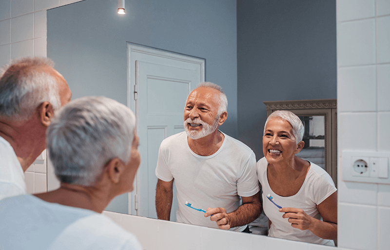 An older couple brushing their teeth together
