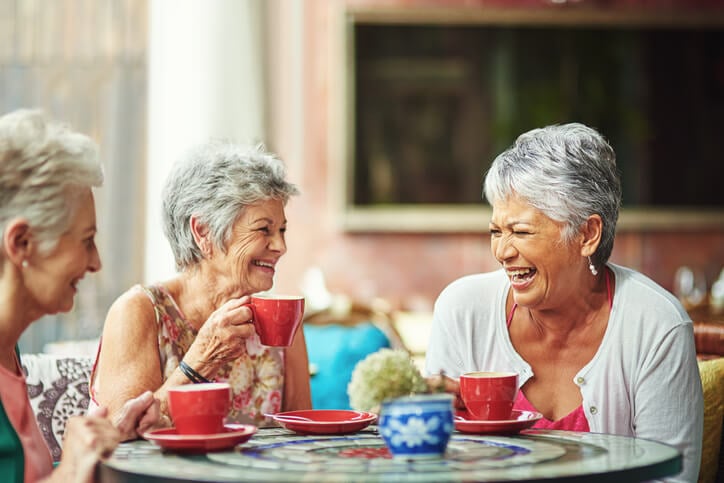 Some older women laughing and drinking tea