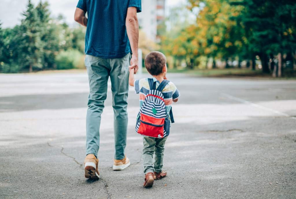 kid with backpack walking with dad