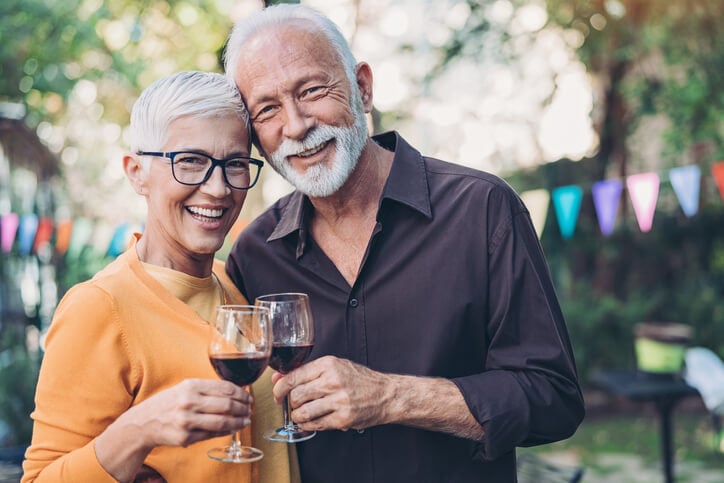 An older couple toasting their wine glasses