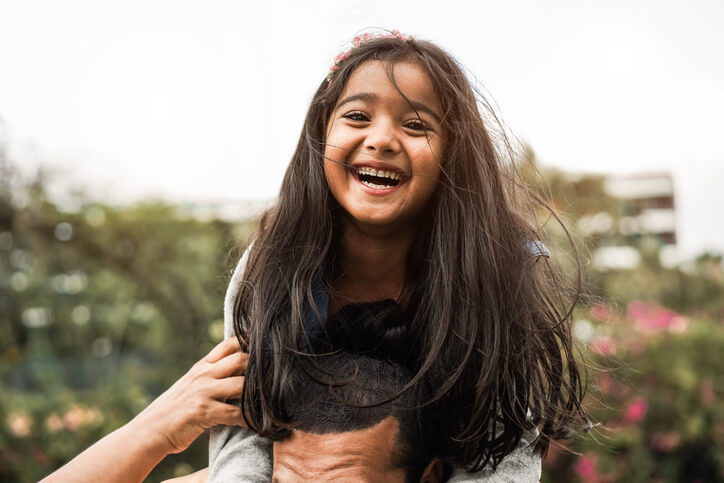 Little girl smiling on her dad's shoulders