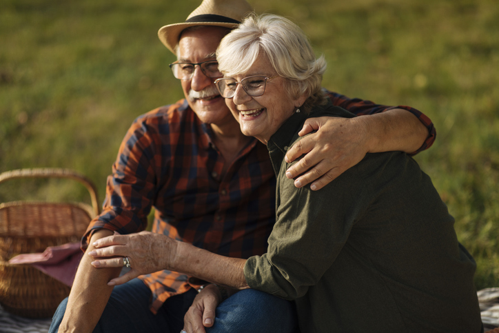 Senior couple embrace affectionately while on a relaxing picnic outdoors