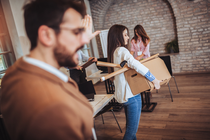 Business woman carrying packing up all his personal belongings and files into a brown cardboard box to resignation in modern office, resign concept.