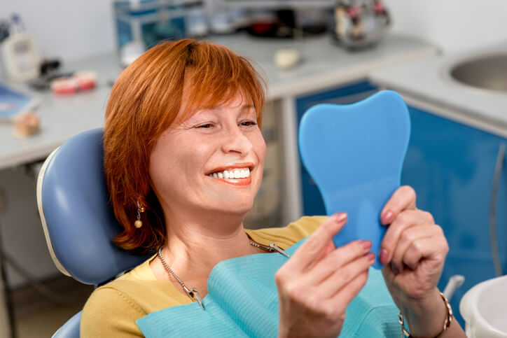 woman holding mirror and smiling