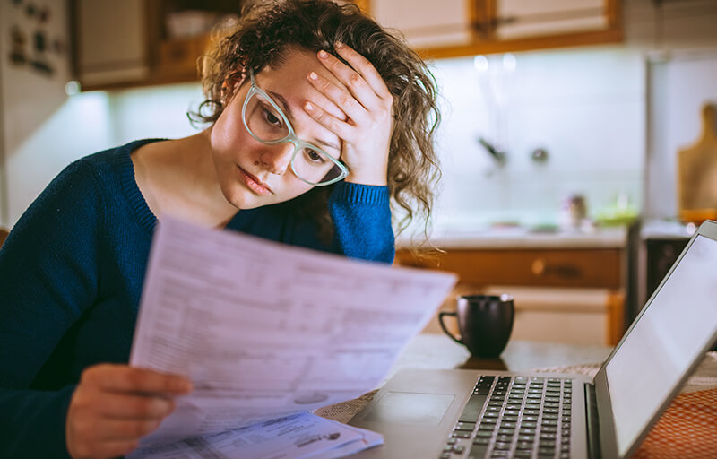 A woman looking in dismay at some bills