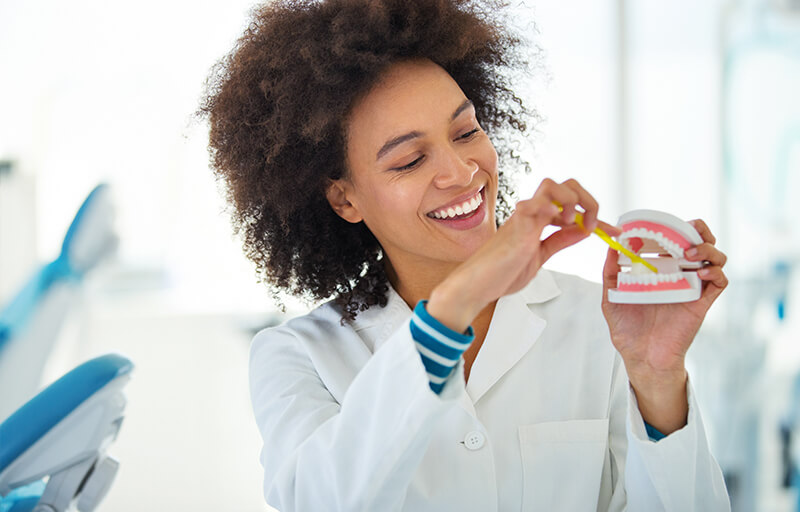 A woman demonstrating how to brush on some chompers