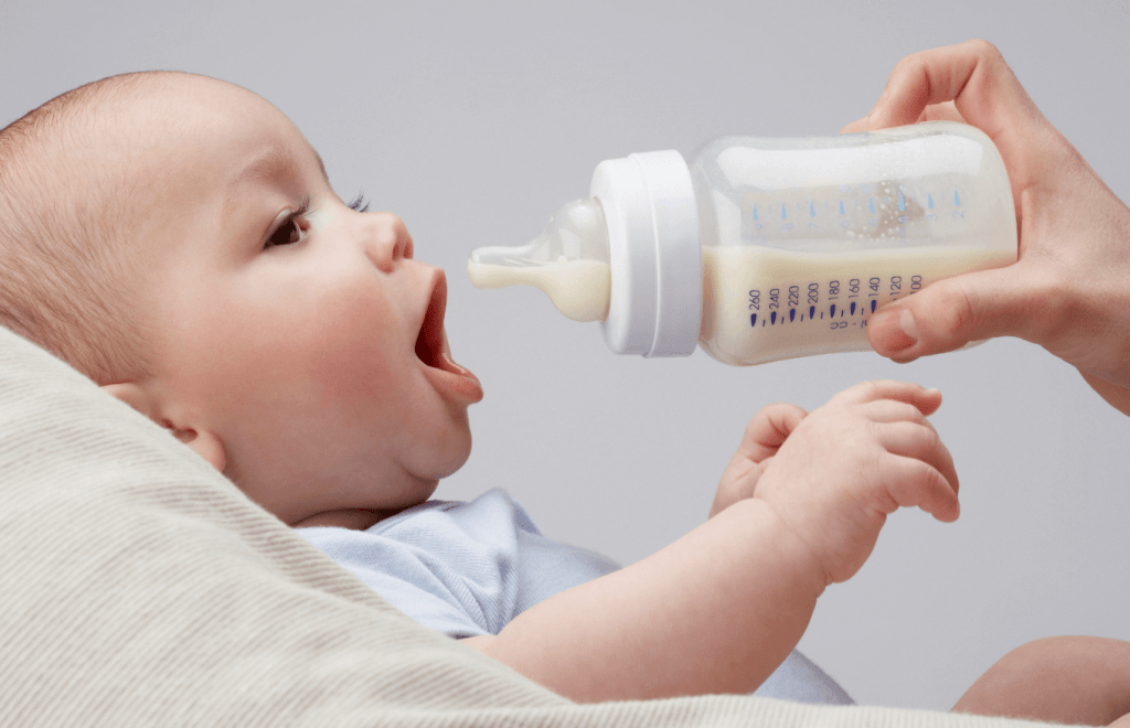 A baby about to nurse from a bottle