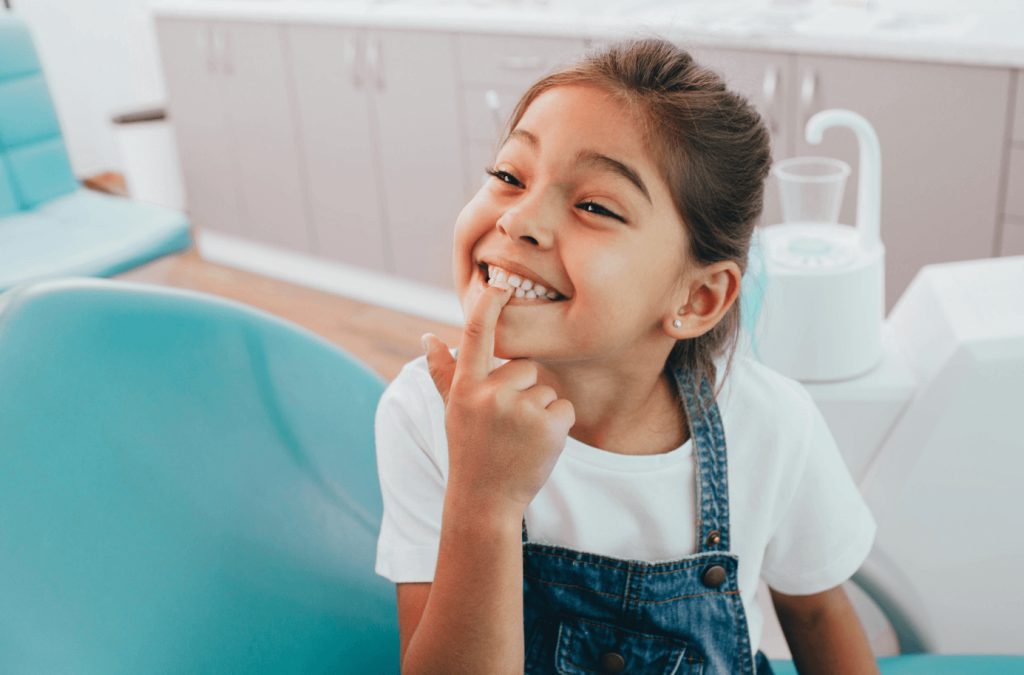 A child at the dentist pointing to her smile