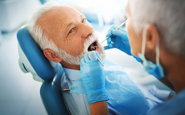 man being tended to by dentist