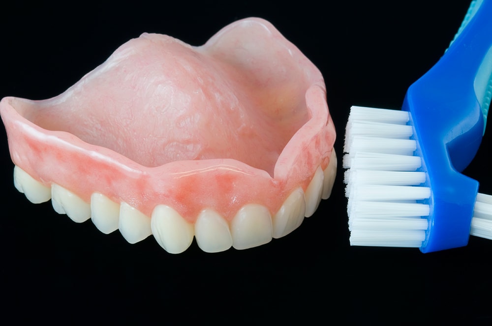 Brushing dentures with a toothbrush