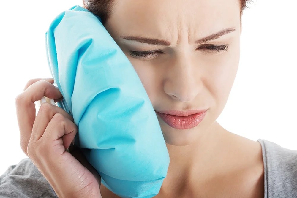 Woman holding ice pack on side of jaw