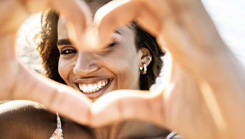 Girl smiling with her hands in the shape of a heart