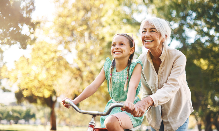 Shot of a senior woman teaching her granddaughter how to ride a bike