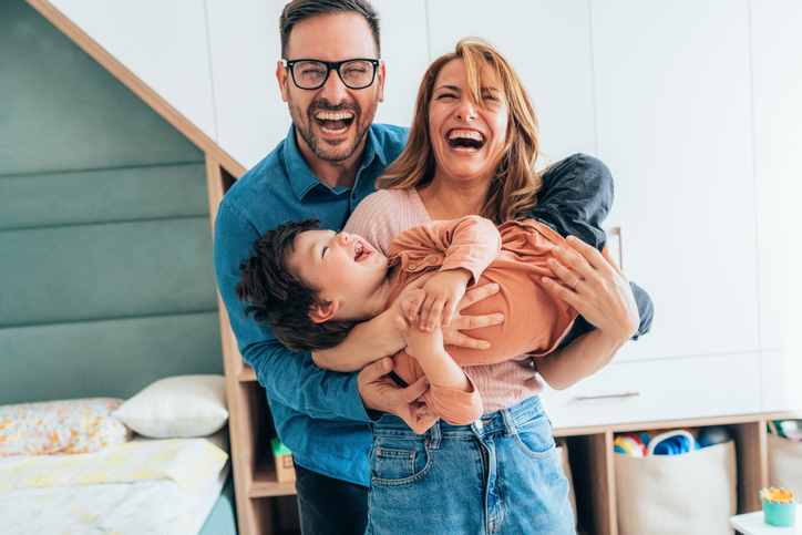 Mother, father and toddler boy playing together at home. Happy family having fun. Young parents playing with their child.