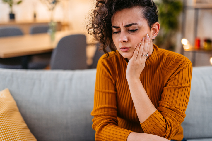 Beautiful young woman having toothache at home.