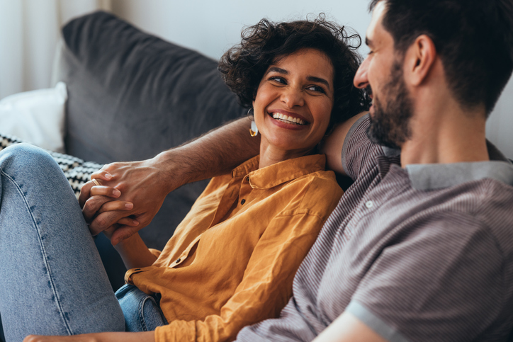 A Happy Beautiful Couple Sitting On The Cozy Sofa At Home And Relaxing