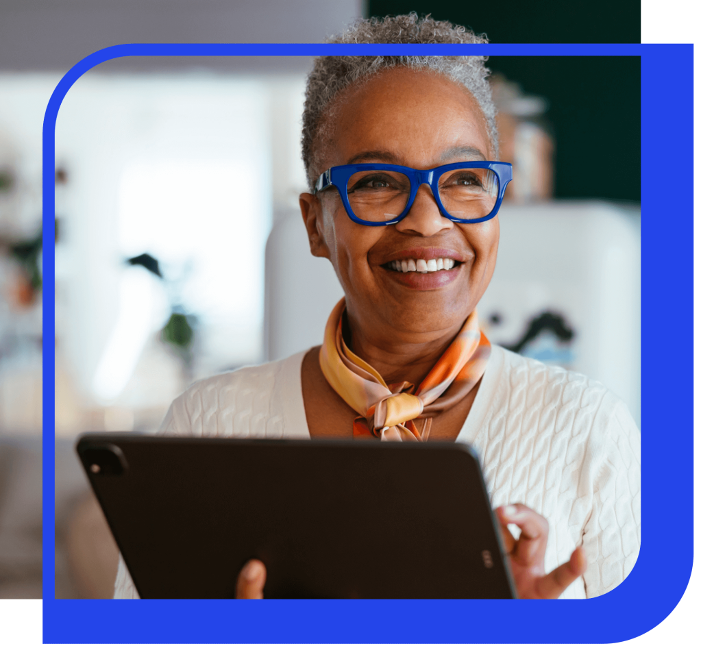 women with blue glasses smiling while using a tablet
