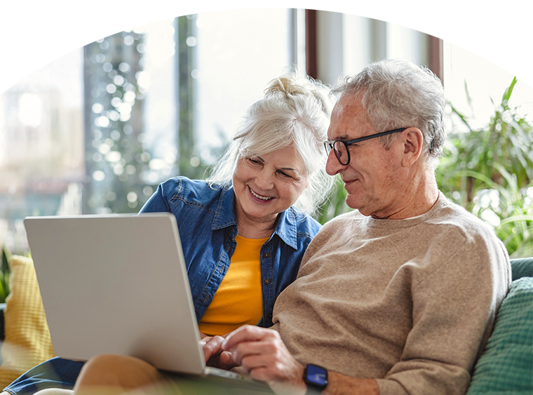 Old couple smiling and looking at laptop