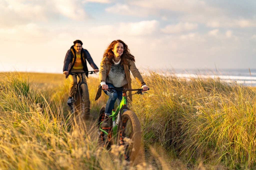 Young couple ride bikes on coastal trail