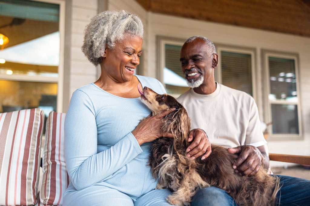 Senior couple at home cuddling with their longhaired dachshund dog