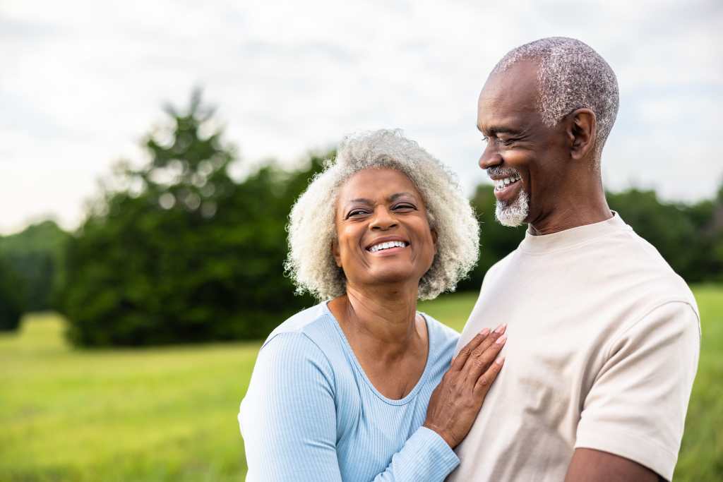 Senior black couple laughing together during exercise outdoors in field