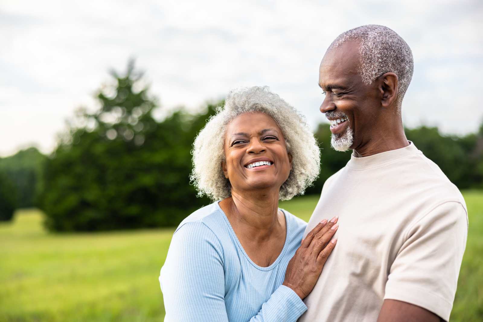 Senior black couple laughing together during exercise outdoors in field
